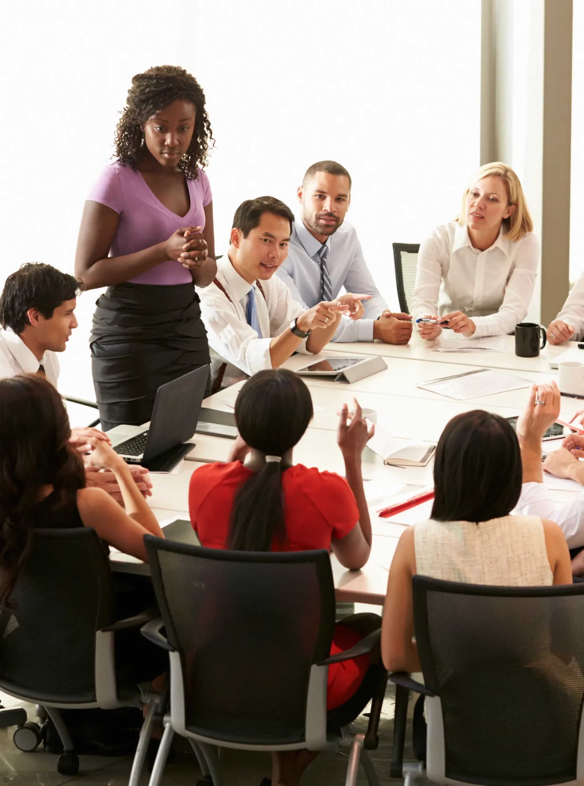 A woman stands and speaks to a table of other professionals